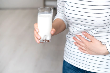 Lactose intolerance, health problem with dairy food products concept. Woman holding glass of milk having bad stomach ache.