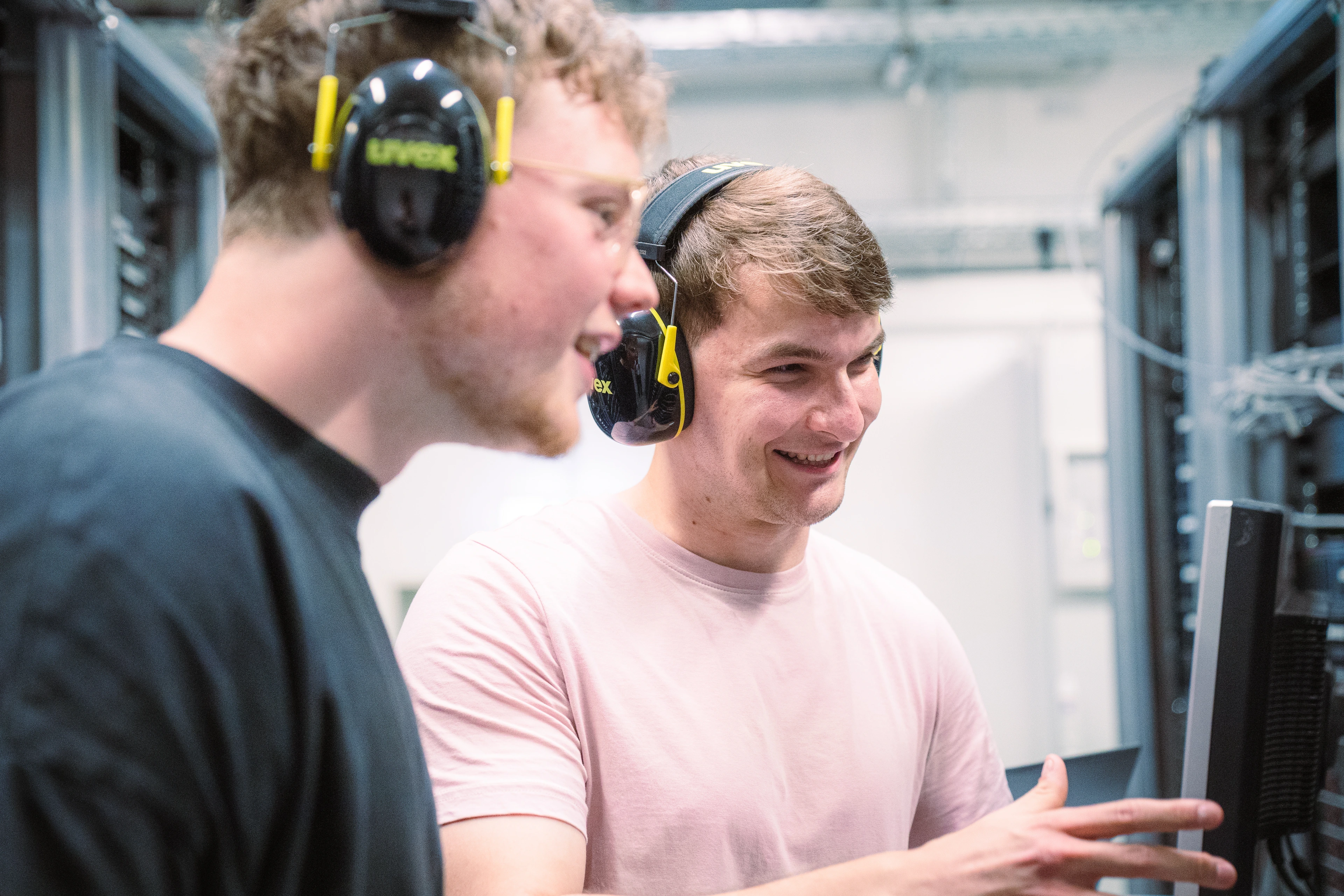 IT specialists in front of a computer wearing headphones