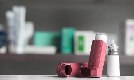 Asthma inhalers on table against blurred background. Space for text