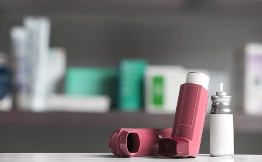 Asthma inhalers on table against blurred background. Space for text
