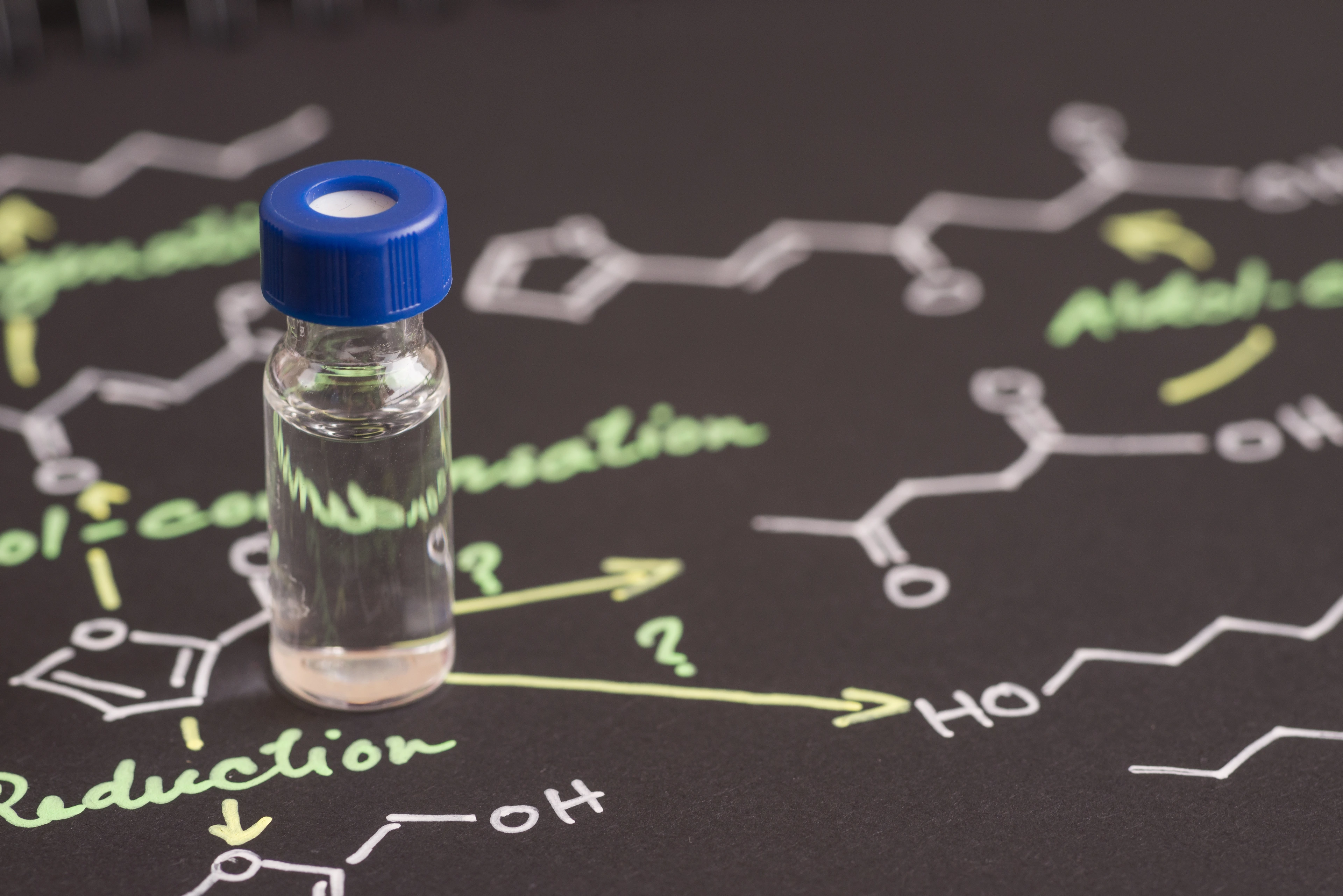 Close-up blue cap sample vial on paper with chemical formula