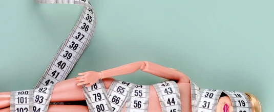 Doll wrapped in measuring tape. Tied up unrecognizable plastic doll, weight loss, fasting and slimming, diet, anorexia, overeating control, female fight for perfect fit body concept. Free copyspace