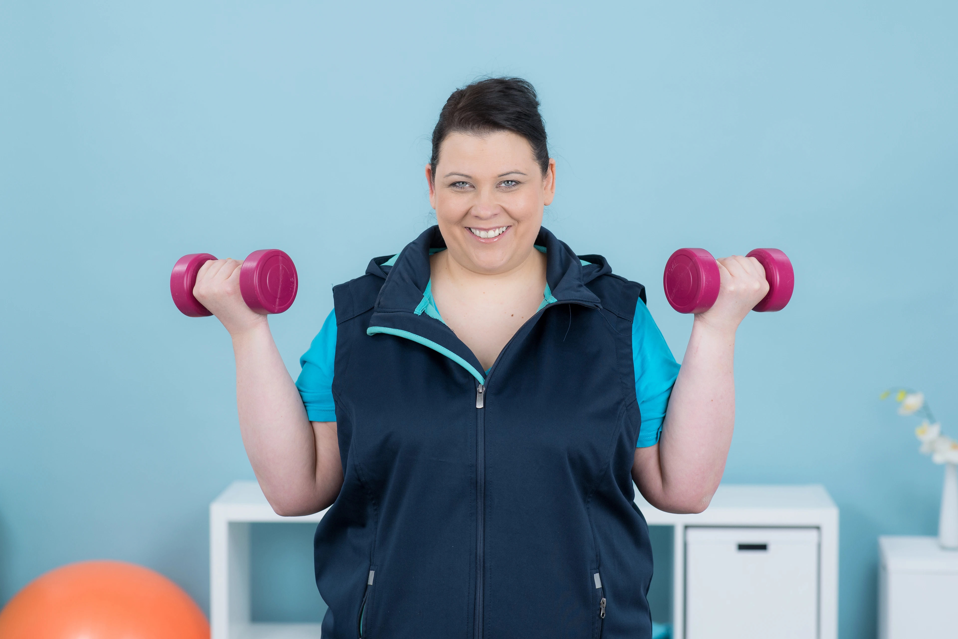 übergewichtige junge frau trainiert mit hanteln