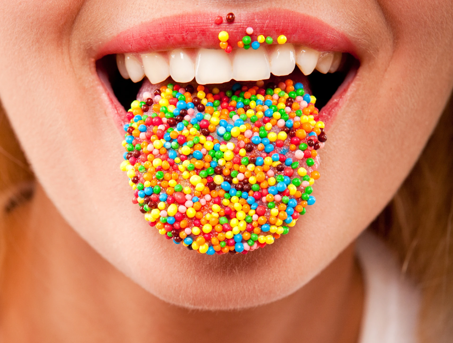 many color bright candies on female tongue