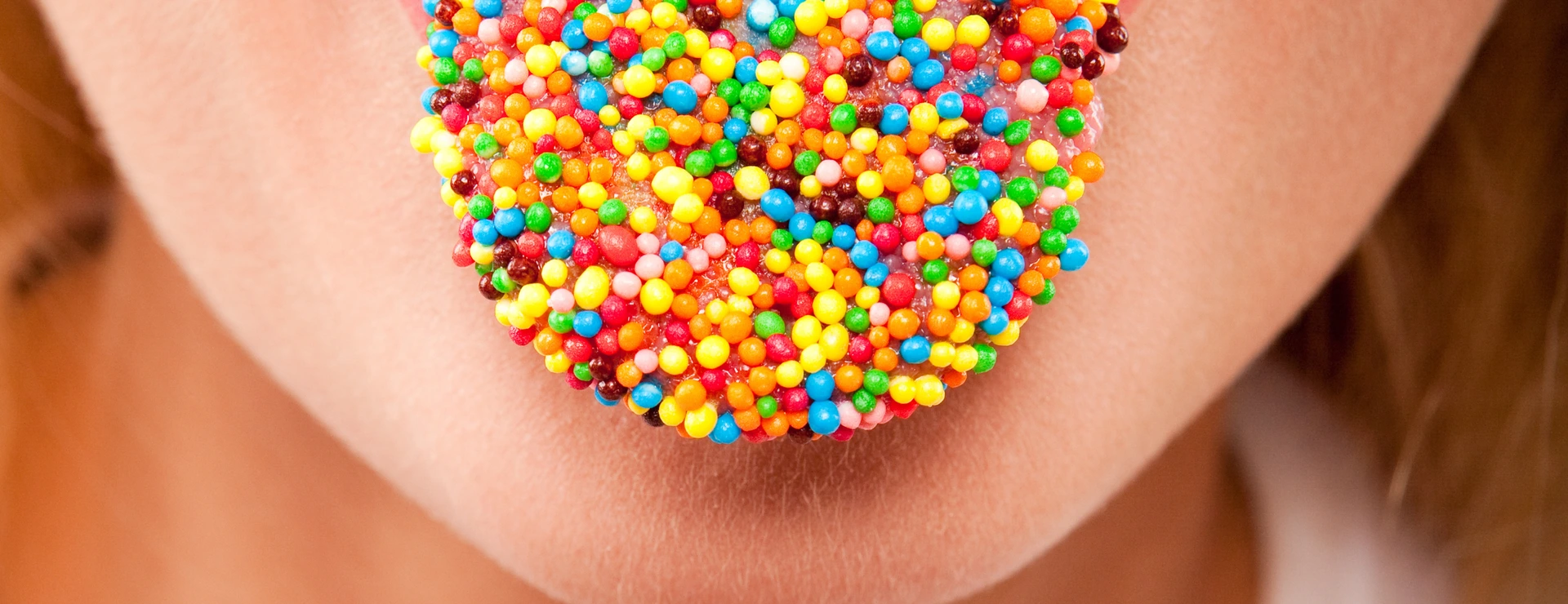 many color bright candies on female tongue