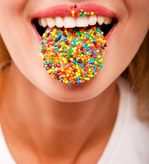 many color bright candies on female tongue