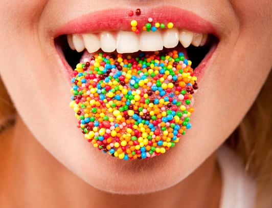 many color bright candies on female tongue