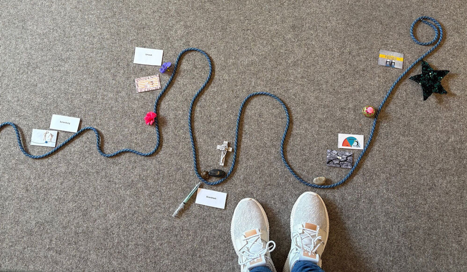 Eine zweite Schnur als Lebenslauf ist zu sehen, davor Füße in Sportschuhen