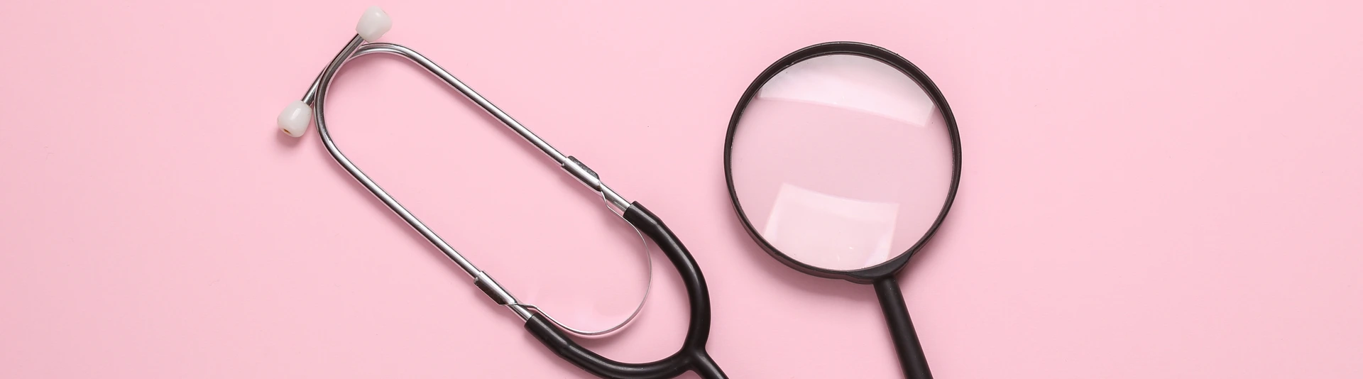 Stethoscope with magnifying glass on pink background. Diagnosis of diseases. Top view