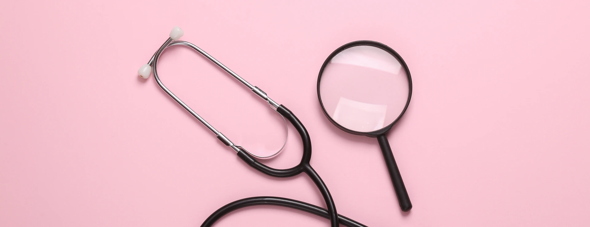 Stethoscope with magnifying glass on pink background. Diagnosis of diseases. Top view