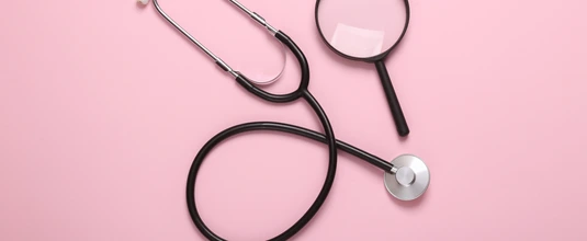 Stethoscope with magnifying glass on pink background. Diagnosis of diseases. Top view