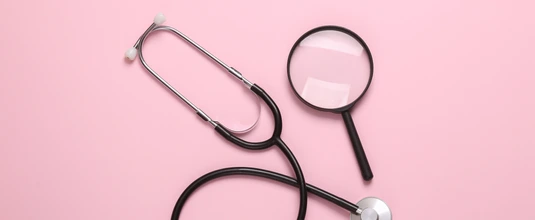 Stethoscope with magnifying glass on pink background. Diagnosis of diseases. Top view