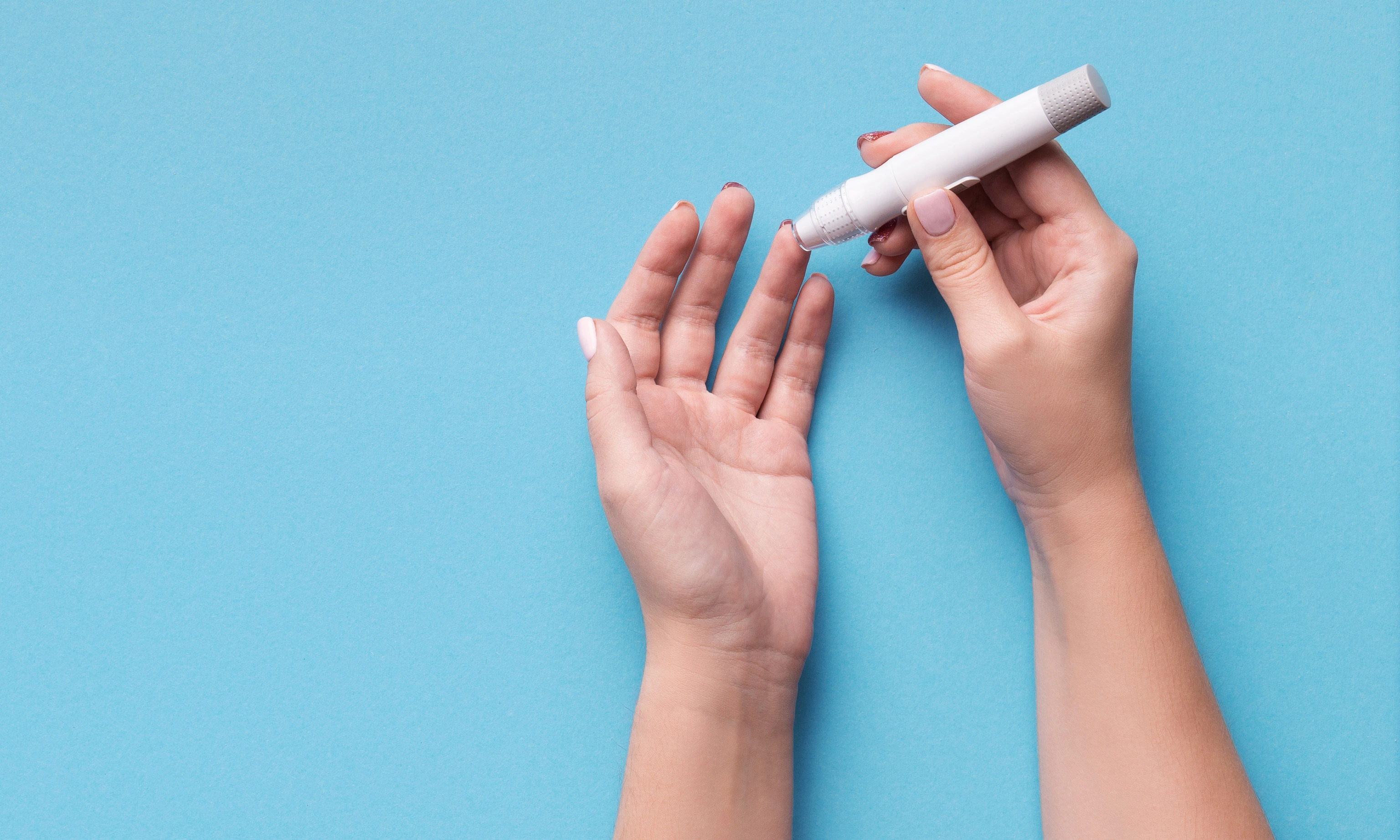 Woman using glucometer on blue background, top view