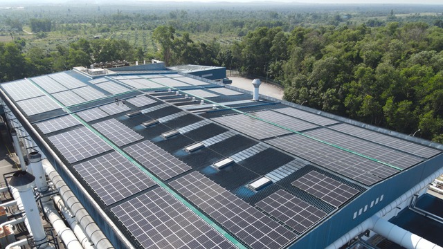 rooftop solar panels with village and forest in background