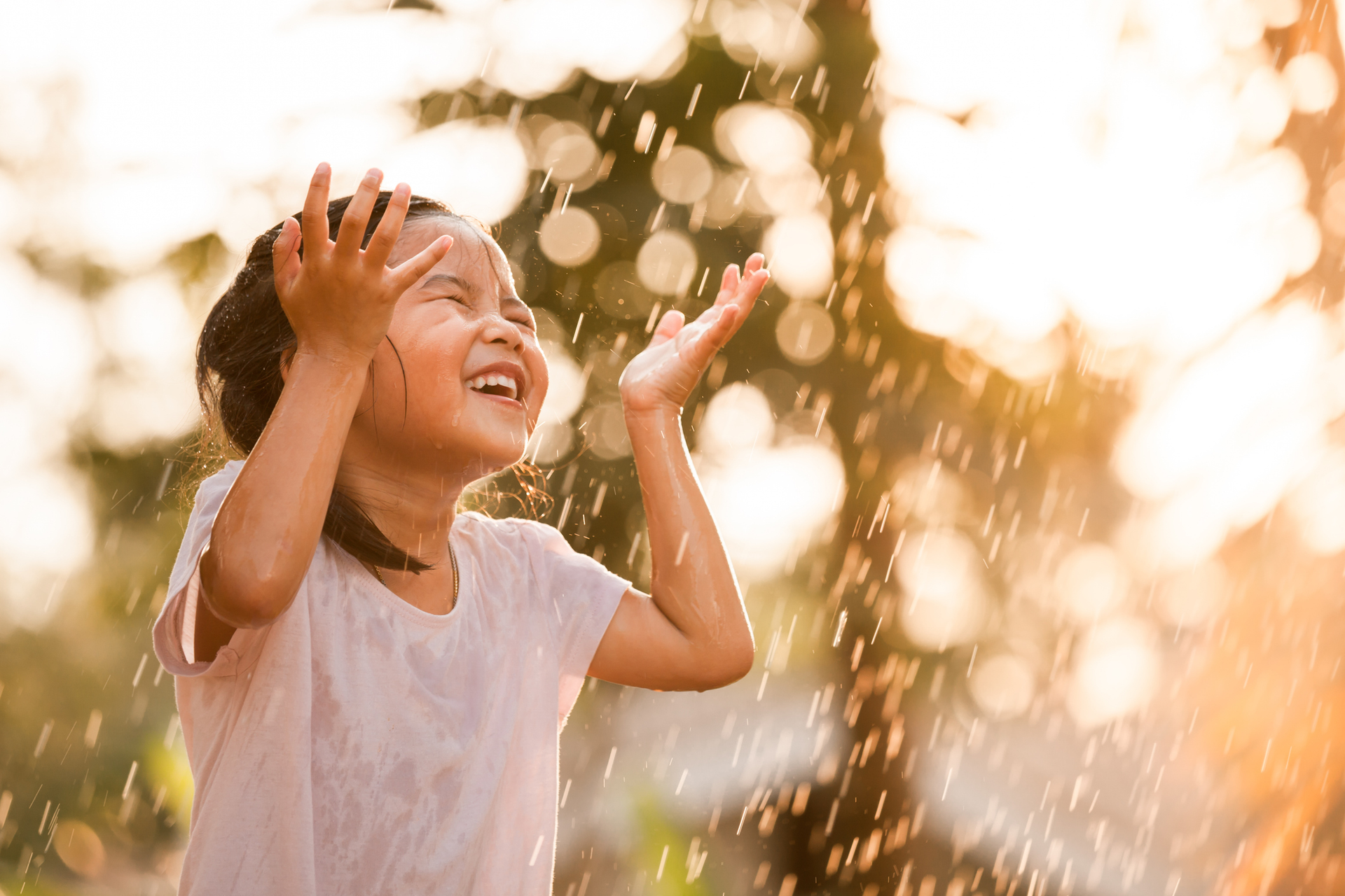 Happy asian little girl having fun to play with the rain