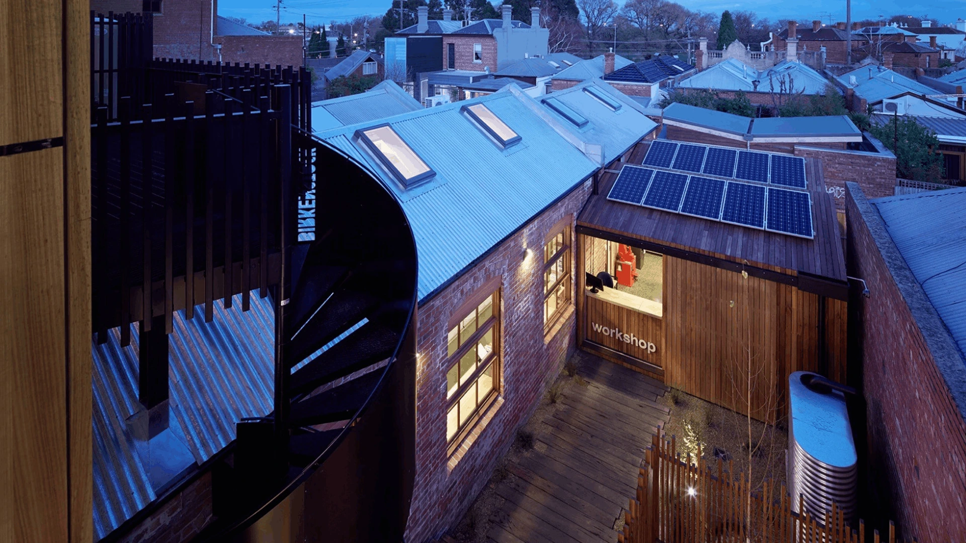 Innenhof bei Dämmerung mit Werkstattraum von PALMBERG, workshop-Beschriftung und Solarmodule