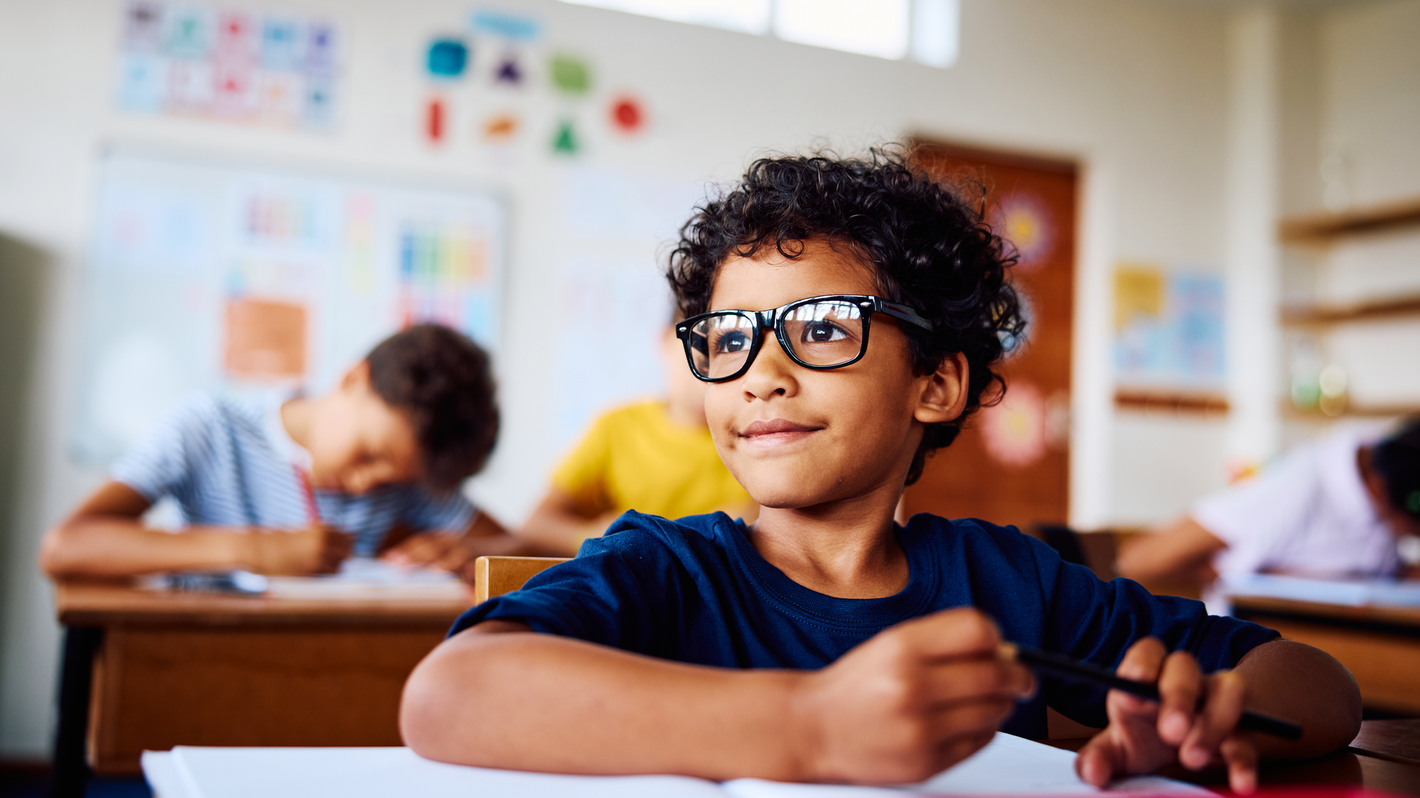Schoolboy sitting at desk, smiling, looking sideways