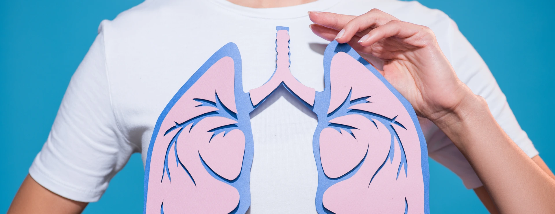 partial view of woman in white tshirt with paper crafted lungs on blue backdrop