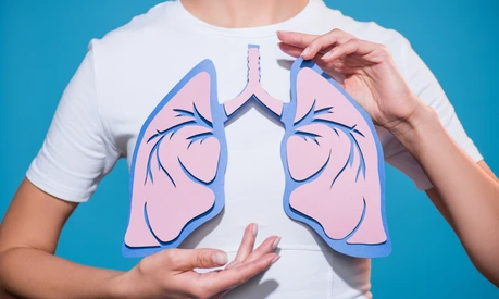 partial view of woman in white tshirt with paper crafted lungs on blue backdrop