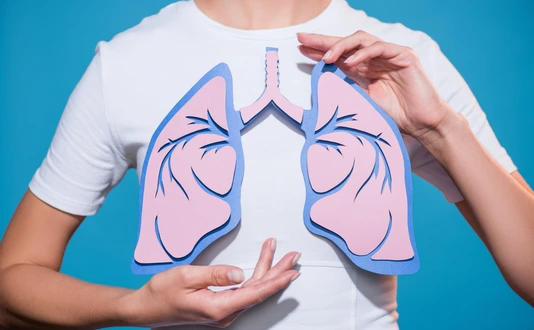partial view of woman in white tshirt with paper crafted lungs on blue backdrop