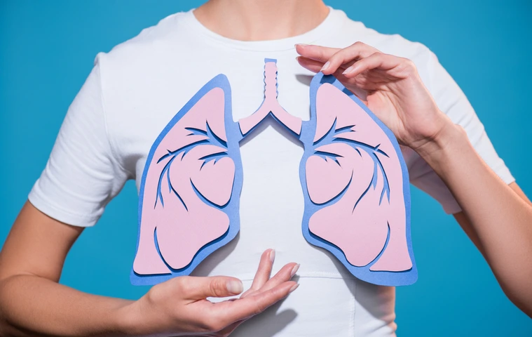 partial view of woman in white tshirt with paper crafted lungs on blue backdrop