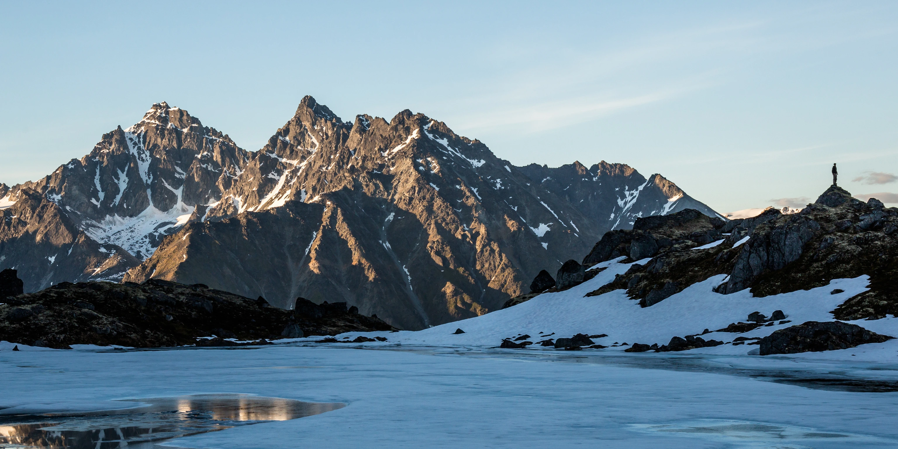 Man standing on ridge reflected in the lake.