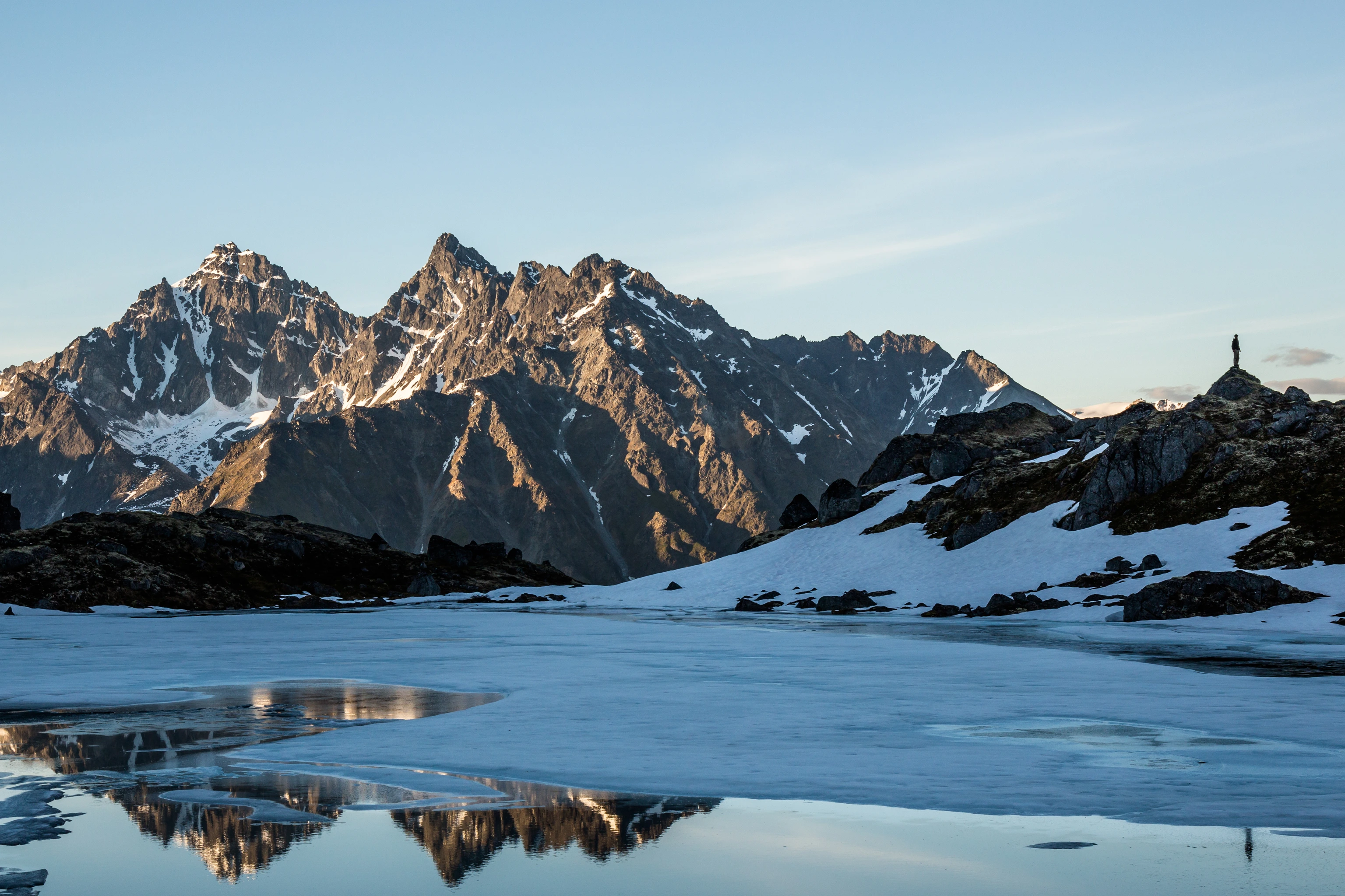 Man standing on ridge reflected in the lake.
