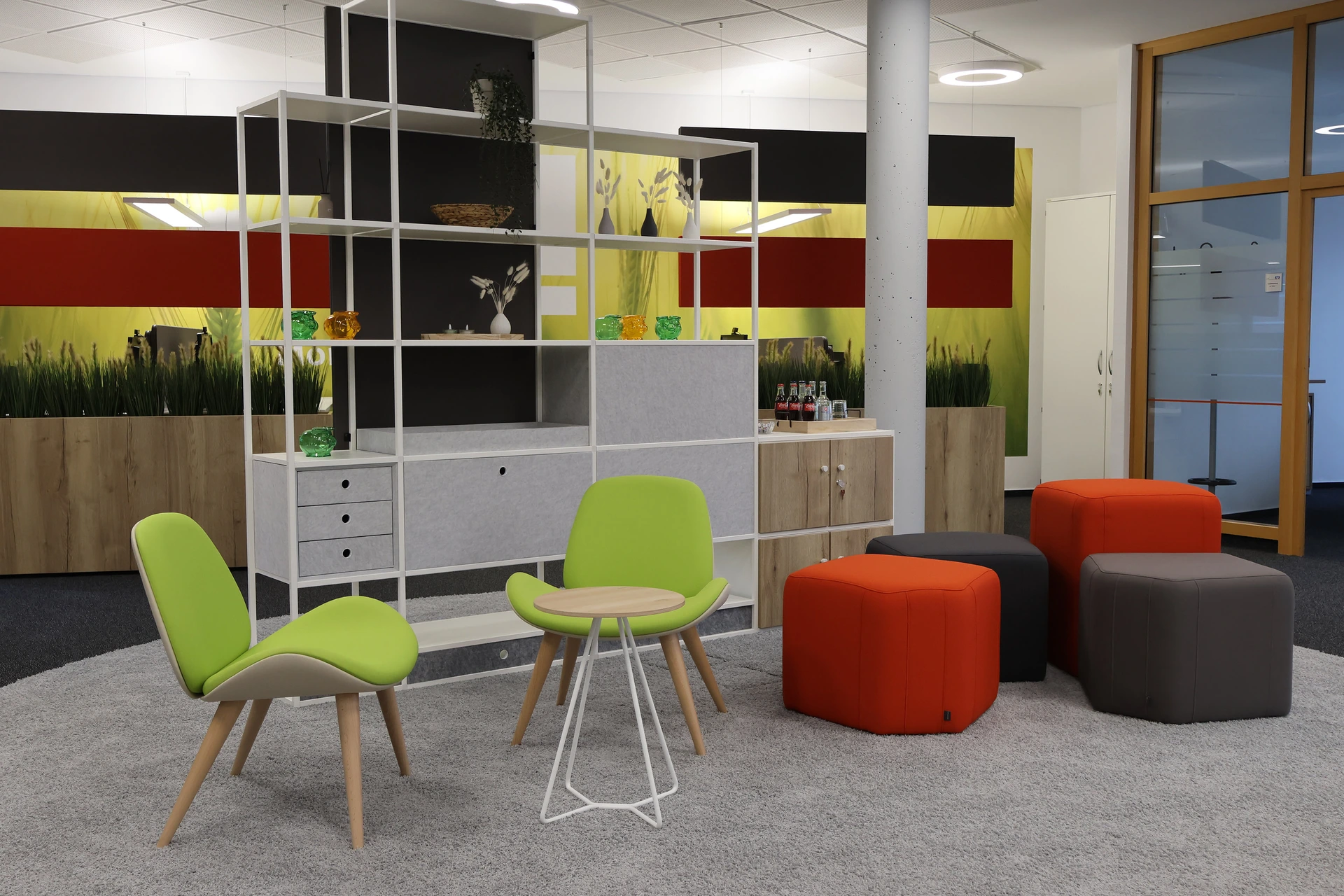 Gemütliche Lounge mit grünen Stühlen, bunten Hockern und modularem PALMBERG-Regalsystem
