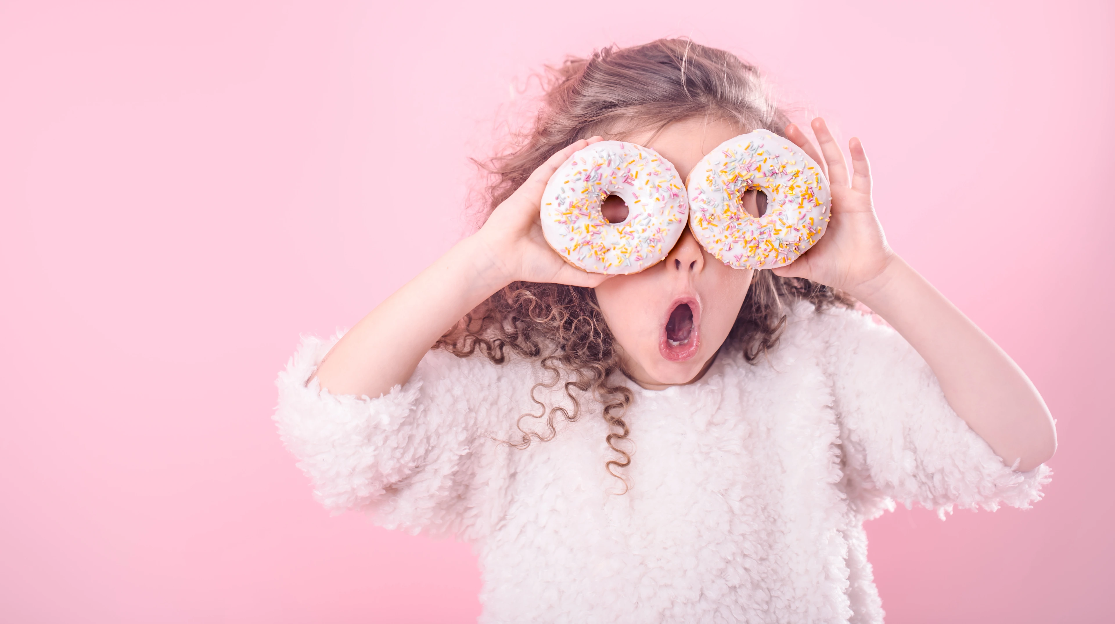 Portrait of a little surprised girl with donuts