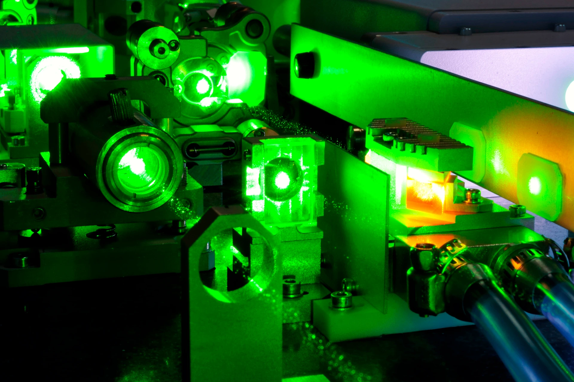 bright green laser light going inside complicate scientific system with cooling hoses inside