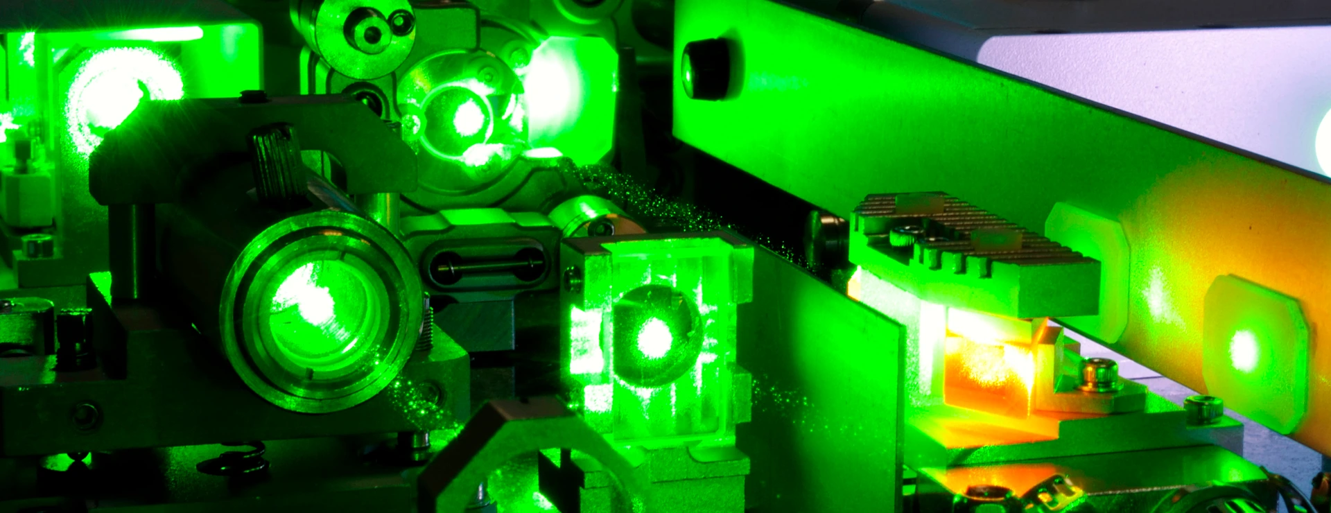 bright green laser light going inside complicate scientific system with cooling hoses inside