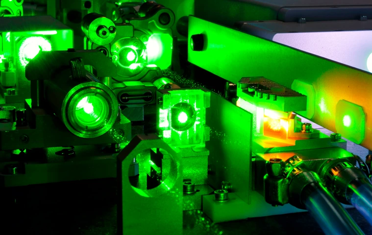 bright green laser light going inside complicate scientific system with cooling hoses inside