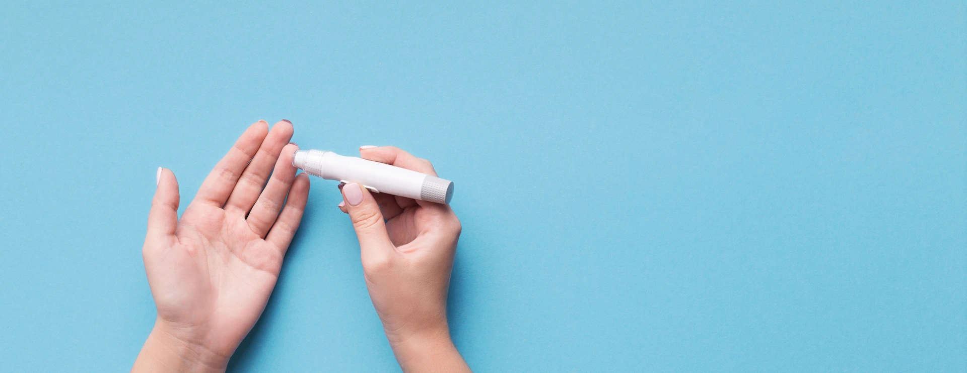 Woman using glucometer on blue background, top view