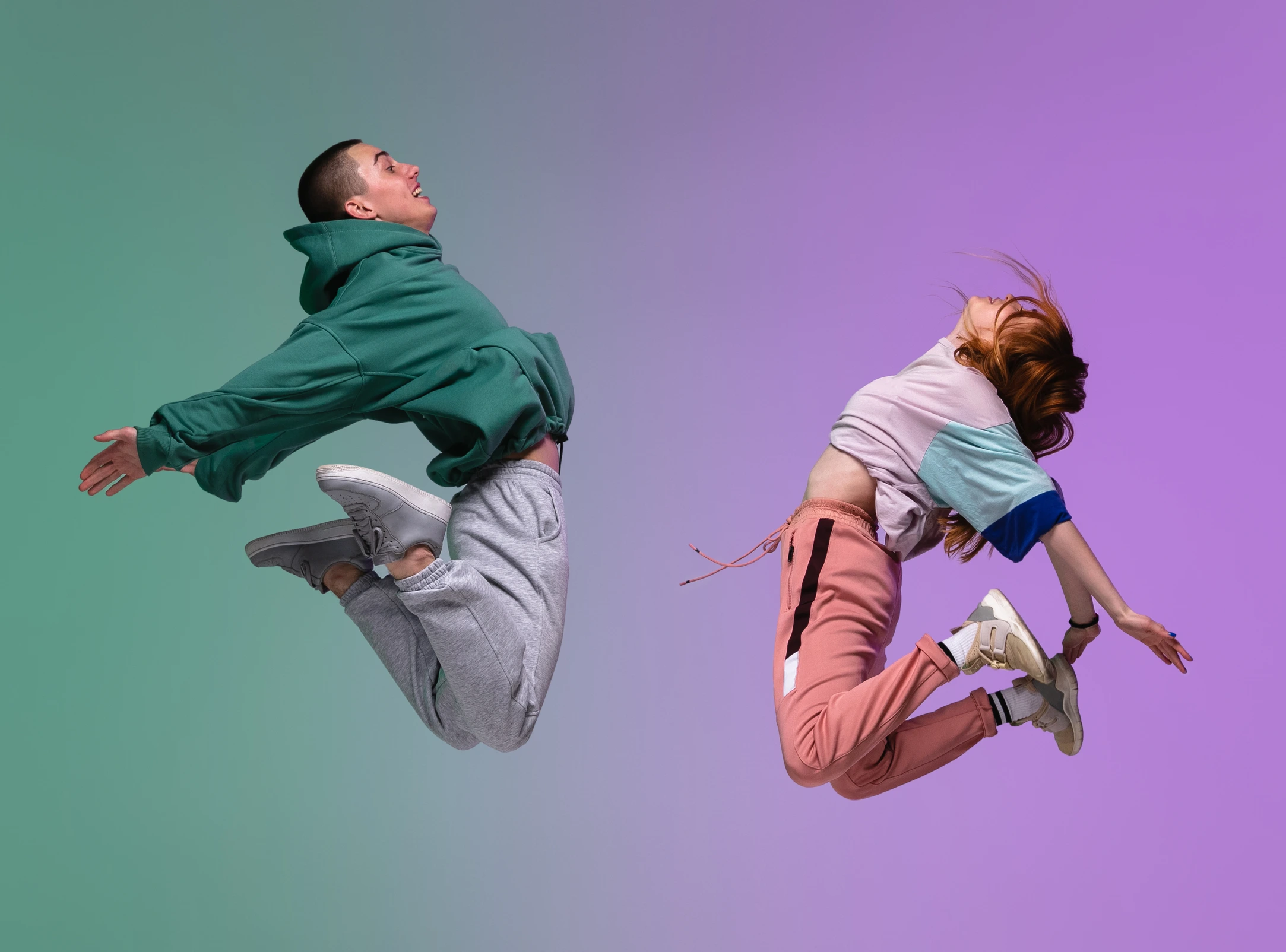 Boy and girl dancing hip-hop in stylish clothes on gradient background at dance hall in neon light.