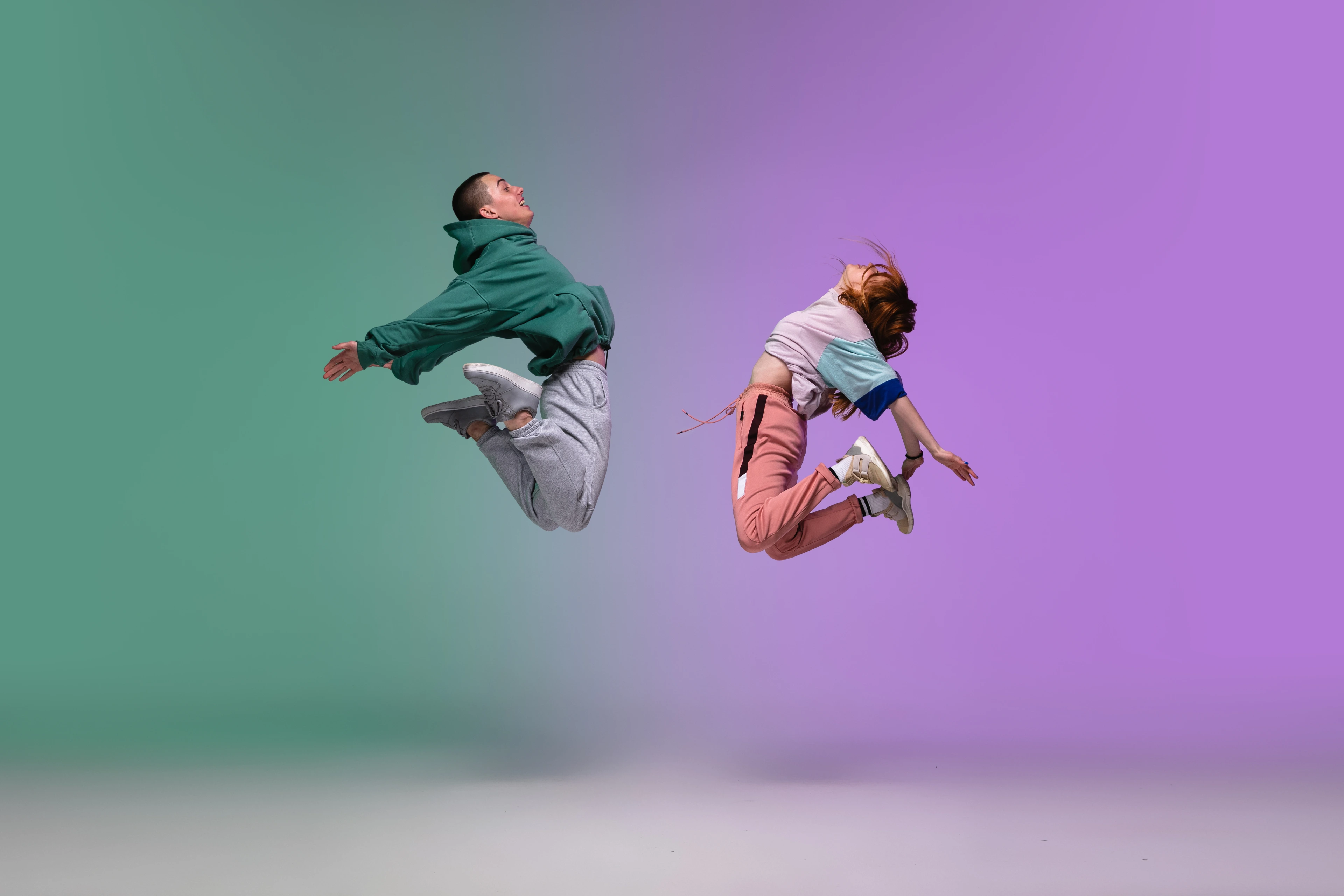 Boy and girl dancing hip-hop in stylish clothes on gradient background at dance hall in neon light.