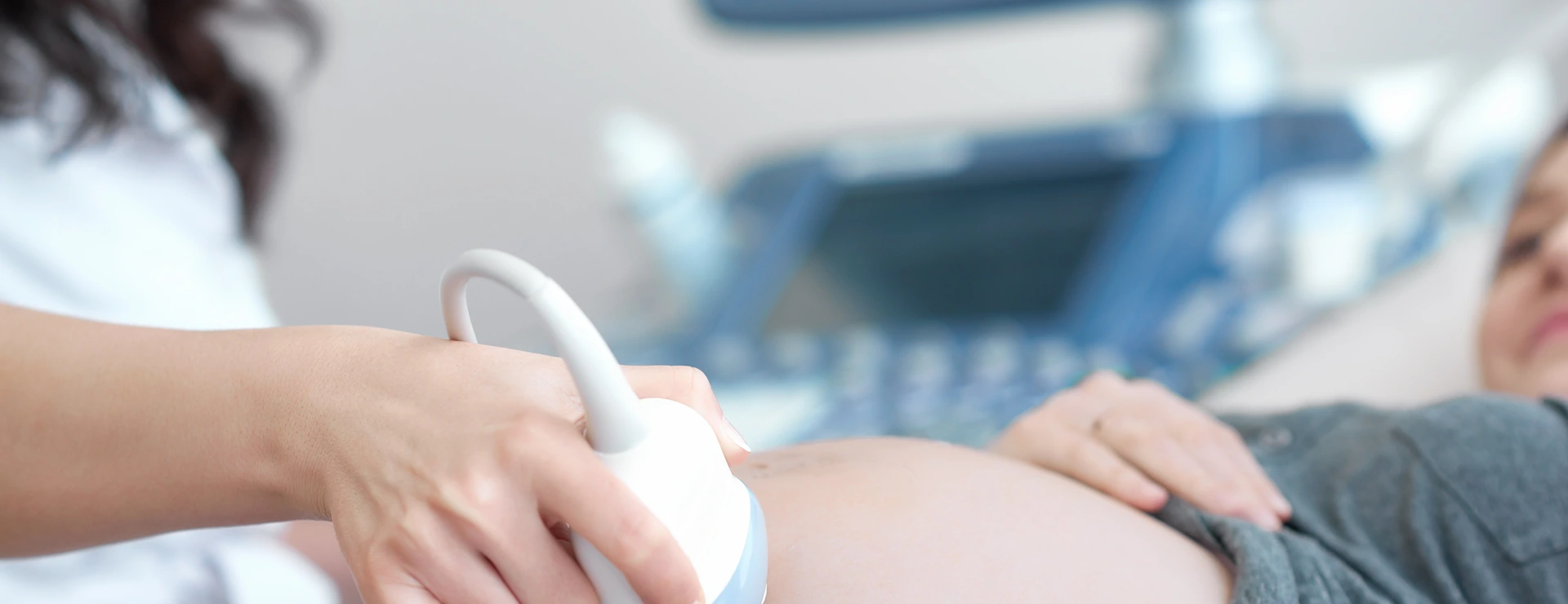 Doctor using ultrasound equipment screening of pregnant woman.