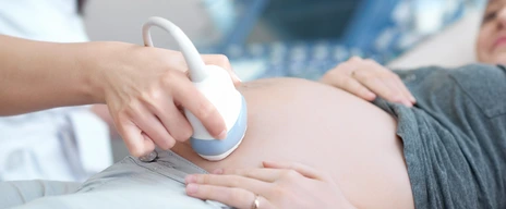 Doctor using ultrasound equipment screening of pregnant woman.