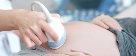 Doctor using ultrasound equipment screening of pregnant woman.
