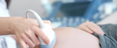 Doctor using ultrasound equipment screening of pregnant woman.