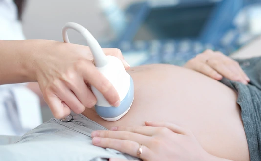 Doctor using ultrasound equipment screening of pregnant woman.