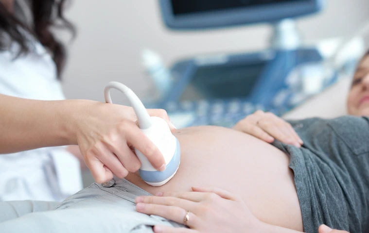 Doctor using ultrasound equipment screening of pregnant woman.