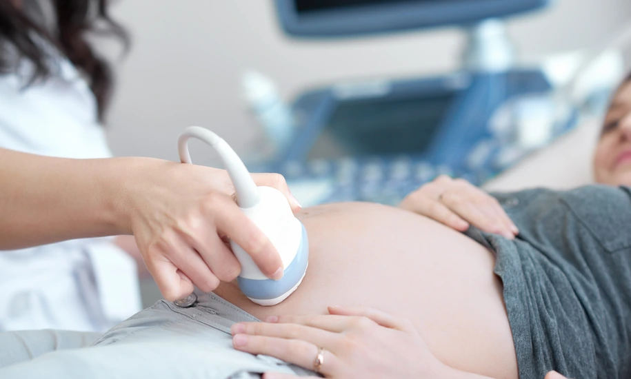 Doctor using ultrasound equipment screening of pregnant woman.