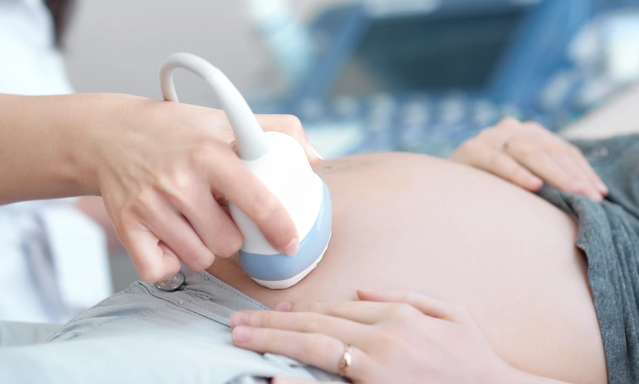 Doctor using ultrasound equipment screening of pregnant woman.