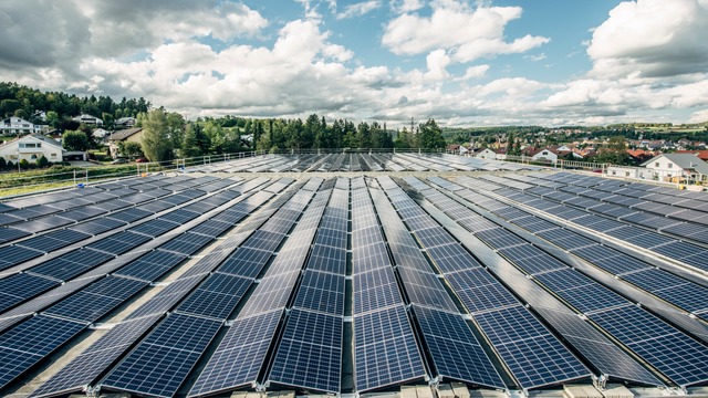 rooftop solar panels with village and forest in background