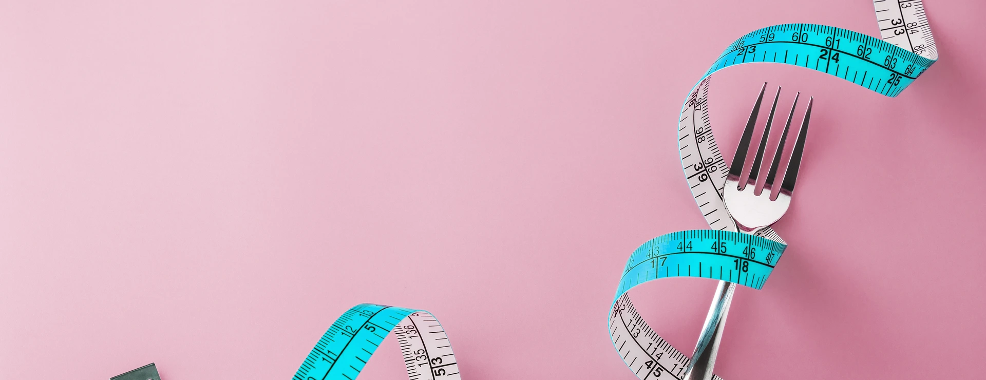 Fork with measuring tape around on pink background