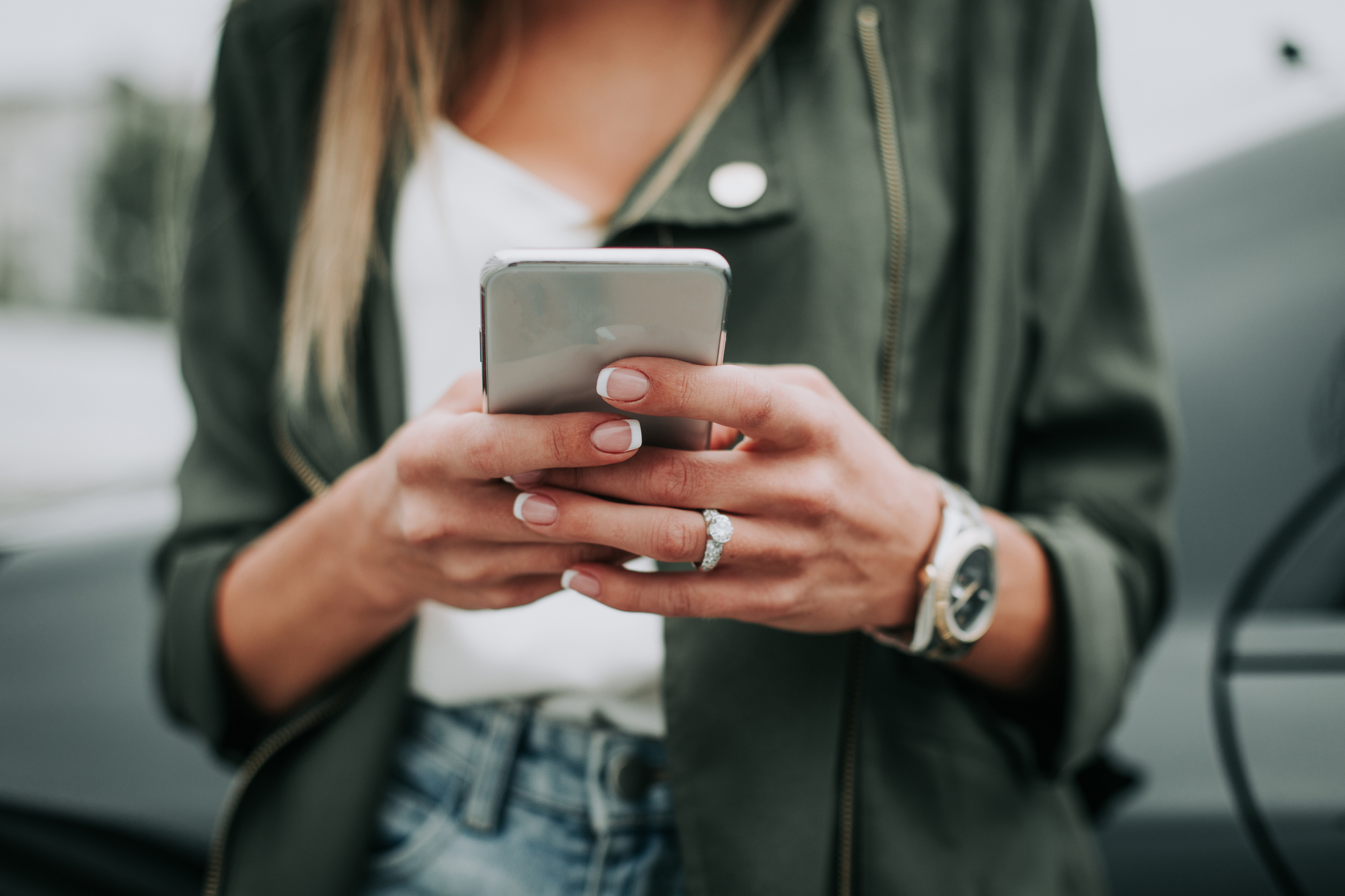 Woman hand typing in the mobile outside