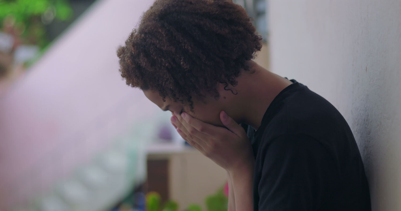 Profil eines männlichen Teenagers, der sich weinend die Hände vors Gesicht hält.