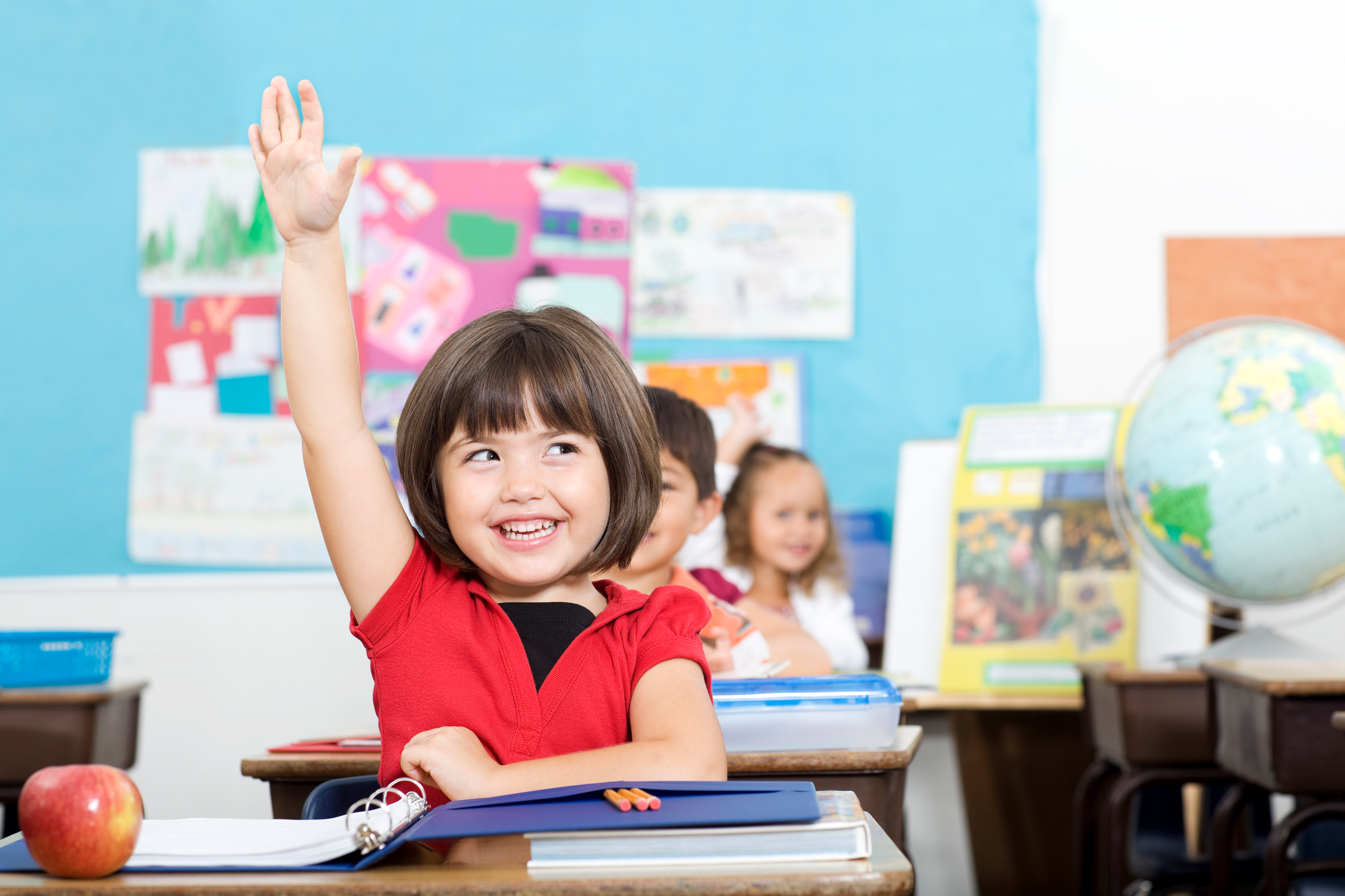 begeistertes Mädchen das sich im Schulunterricht meldet