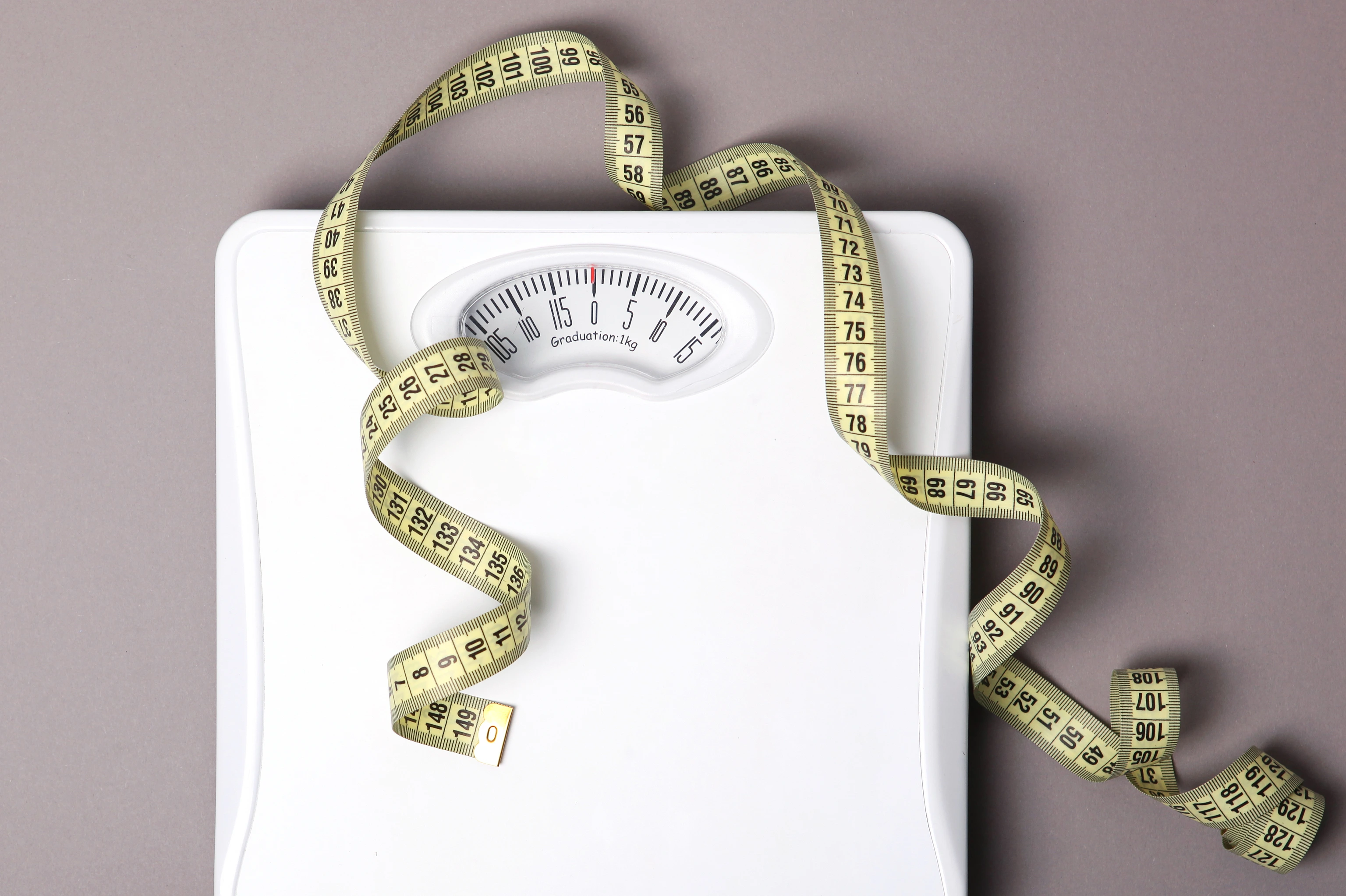 floor scales and tape measure on a colored background top view. Healthy lifestyle concept, healthy eating. Body weight control.