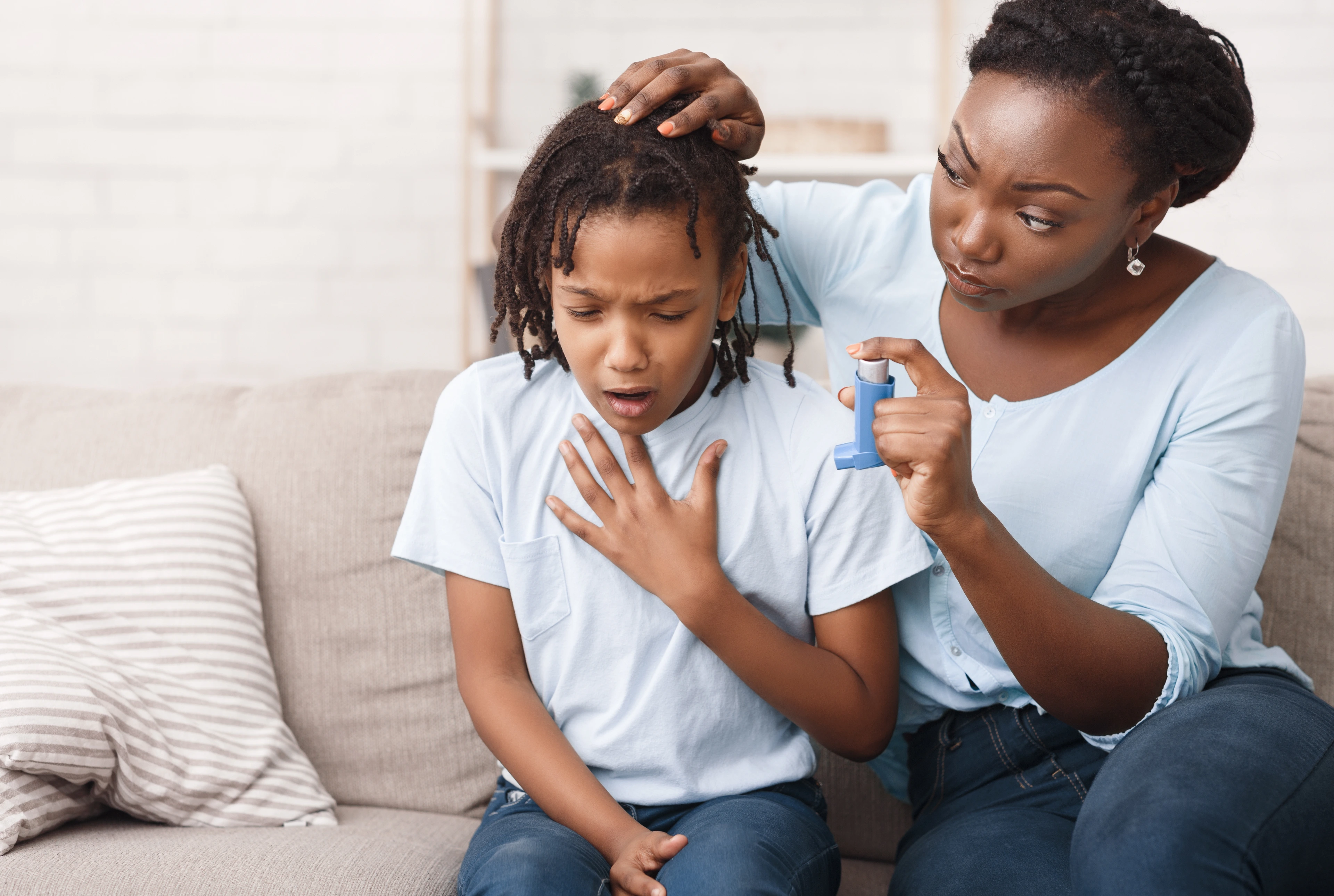 Afro mother holding asthma inhaler for daughter